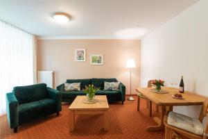 利兴Seehotel Lindenhof的客厅配有两张绿色沙发和桌子