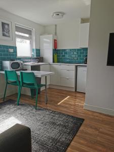 卡迪夫Stylish studio bungalow, close to Cardiff Centre的厨房配有桌子和两把绿色椅子