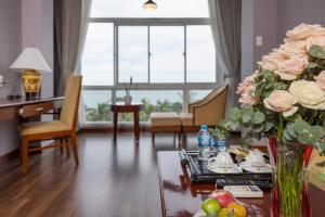 潘郎西贡 - 宁楚度假酒店的客厅配有一张带玫瑰花瓶的桌子