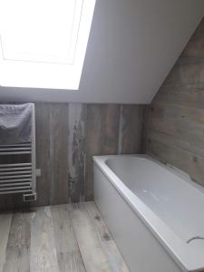 欧丹冈Le Chant des Vagues的浴室配有白色浴缸,设有天窗