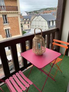 多维尔Duplex au cœur de Deauville avec vue imprenable et parking privé的阳台的粉红色桌子、椅子和鸟笼