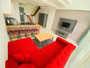 梅尔辛Vm Resort Otel Mersin的一间带红色沙发的客厅和一间厨房