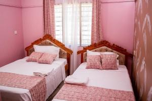 基利菲Dondoo's Paradise- Perfect Vacation Home的配有粉红色墙壁的小客房内的两张床