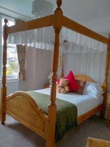 温德米尔德纳哈斯特宾馆的一间卧室配有一张木床,上面有泰迪熊