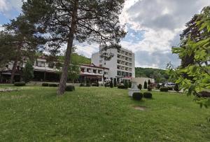 萨拉他蒙蒂鲁Hotel Spa Cazino Monteoru的一座白色的大建筑,在一座建筑前方有草地