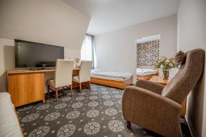 皮耶什佳尼City Hotel的客厅配有电视、书桌和椅子