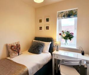 ShirebrookMeadow View, luxury home in heart of England的一间卧室配有一张床、一张书桌和一个窗户。