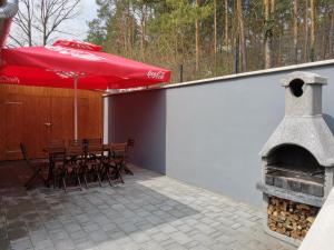 欧尔菲Ady Apartmanház的庭院设有壁炉和带红色遮阳伞的桌子。