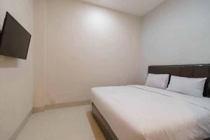 SunggalSeindo Hotel Mitra RedDoorz的一间卧室配有一张床和一台平面电视
