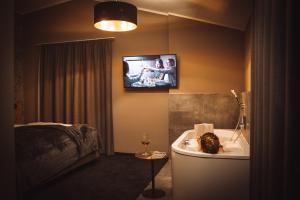 韦斯滕多夫Mountainview Apartments的带浴缸的浴室和墙上的电视
