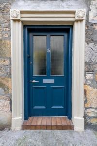 埃尔金The Garden Cottage的一座带石墙的建筑中的一扇蓝色门