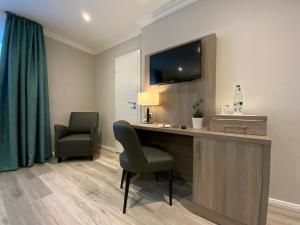 库克斯港Mertinkus Nordseehotel的客房设有一张桌子、一台电视和两把椅子