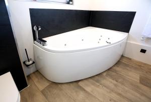 EynattenMarias Guest House的浴室铺有木地板,配有白色浴缸。