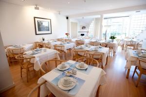 克诺克－海斯特范布恩酒店的餐厅设有白色的桌椅和窗户。