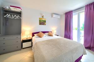 马林斯卡Malinska -Krk的一间卧室配有一张大床和紫色窗帘