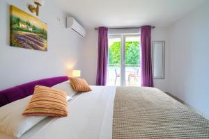 马林斯卡Malinska -Krk的卧室配有一张白色大床和紫色窗帘