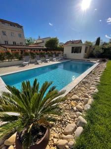 热姆诺普罗旺斯酒店的院子里的游泳池,带椅子和棕榈树