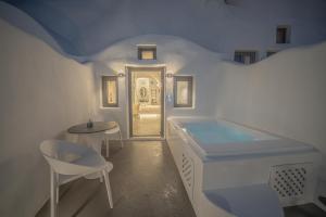 费拉Eternity Suites Santorini的白色的浴室设有浴缸和桌椅。