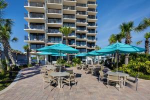 代托纳海滩Nautilus Inn - Daytona Beach的酒店前方设有带桌子和遮阳伞的庭院。
