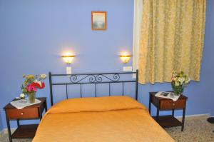 阿吉亚玛丽娜Oasis Hotel Theodoros & Litsa Galaris的一间卧室配有橙色的床和两张鲜花桌