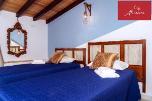 阿尔曼萨Guest House Almeixar的配有两张蓝色床单和镜子的客房内的床铺