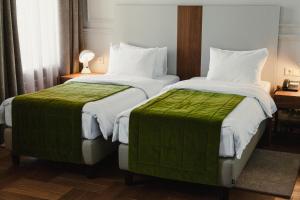 伊尔库茨克Hotel Amurskiy的酒店客房内的两张床,配有绿色床单