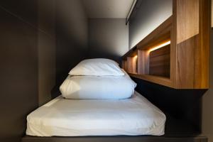 福冈UNPLAN Fukuoka的小房间的小床,带枕头