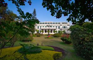 加德满都Hotel Shanker-Palatial Heritage Kathmandu的一座白色的大建筑,前面有一个花园