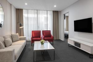 悉尼赖德北梅里顿公寓式酒店的客厅配有沙发和2把红色椅子