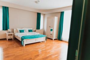 锡比乌Pensiunea Green Villa的一间卧室配有一张带绿色窗帘的床,铺有木地板