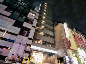 东京HOTEL LiVEMAX Akabane-Ekimae的停在高楼前的自行车