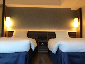 松江市松江东优美好酒店的配有白色床单的酒店客房内的两张床