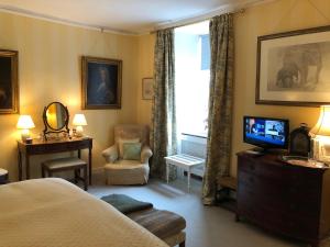 格兰瑟姆Marston Hall的一间卧室配有一张床、一台电视和一把椅子