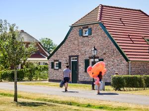 罗赫尔Nice farmhouse villa with PlayStation, in Limburg的男人和女人在建筑物前走