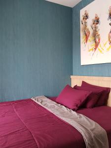 日惹Apartemen Taman Melati Sinduadi 60的一间卧室配有一张紫色床单的床
