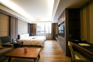 台南塔木德酒店Classic 台南台南馆的酒店客房配有床、沙发和桌子。