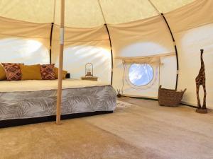 EleoúsaVinSan Glamping & Wellness Centre的一间卧室配有一张床,帐篷内设有一个长颈鹿