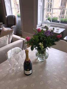 斯坦福德St Martins Apartment Stamford的鲜花桌子上的一瓶葡萄酒和玻璃杯