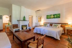 塔里法Hotel-Apart CORTIJO LAS PIÑAS的一间卧室设有两张床、一张桌子和一个壁炉