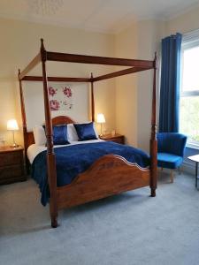 绍斯波特Edendale House的一间卧室配有天蓬床和蓝椅