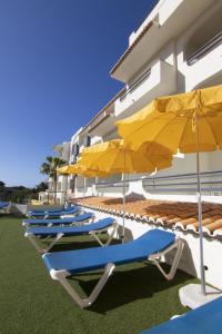 阿尔布费拉Luna Miramar Club的大楼旁的四把躺椅和遮阳伞