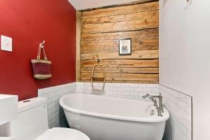 魁北克市Les Appartements du 790的浴室配有白色浴缸和木墙