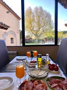 卡斯特罗·德波利亚斯Masia Ca La Caputxeta & Golf的餐桌,盘子上放着食物和饮料,窗户