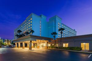 奥兰多Holiday Inn & Suites Across From Universal Orlando, an IHG Hotel的一座大型蓝色建筑,前面有棕榈树