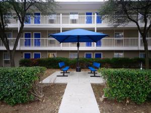 卡罗尔顿InTown Suites Extended Stay Carrollton TX - Westgrove Drive的大楼前的蓝色遮阳伞和椅子