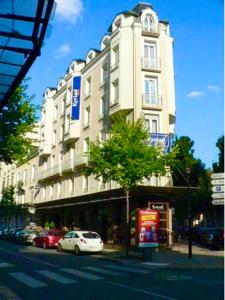 维希Kyriad Restaurant Centre SPA Vichy的停在高楼前的白色汽车