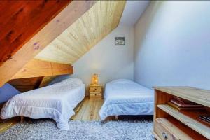 圣拉里苏朗Appartement style chalet à Saint Lary Soulan.的阁楼卧室设有两张床和木制天花板