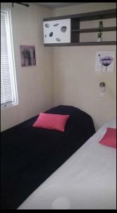 卢贝新城Mobilhomme bungalow 6 personnes villeneuve loubet marina baie des anges的卧室配有黑色和白色的床以及粉红色枕头
