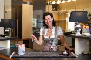 德意志兰茨贝格盖尔尼普尔兹酒店的站在柜台后面的女人,桌子上有蛋糕