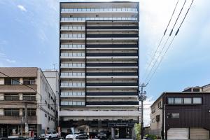 大阪谷町君ホテル　難波80的一座高大的建筑,前面有汽车停放